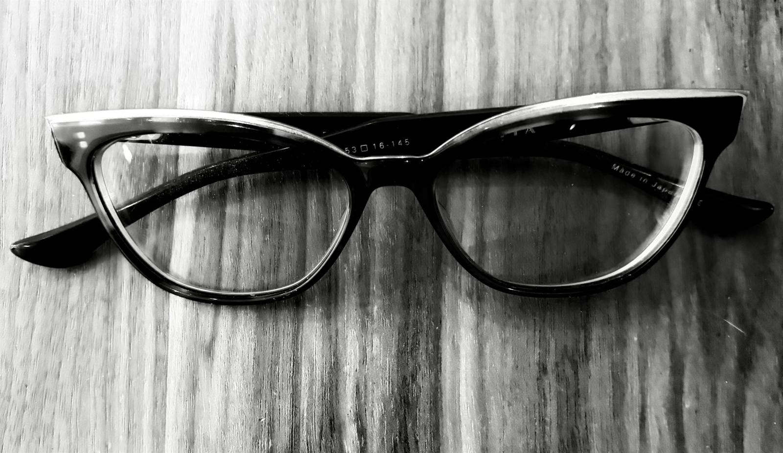 Cat-eye eyeglass frames on a wooden table at Pelini Eyecare in Chicago