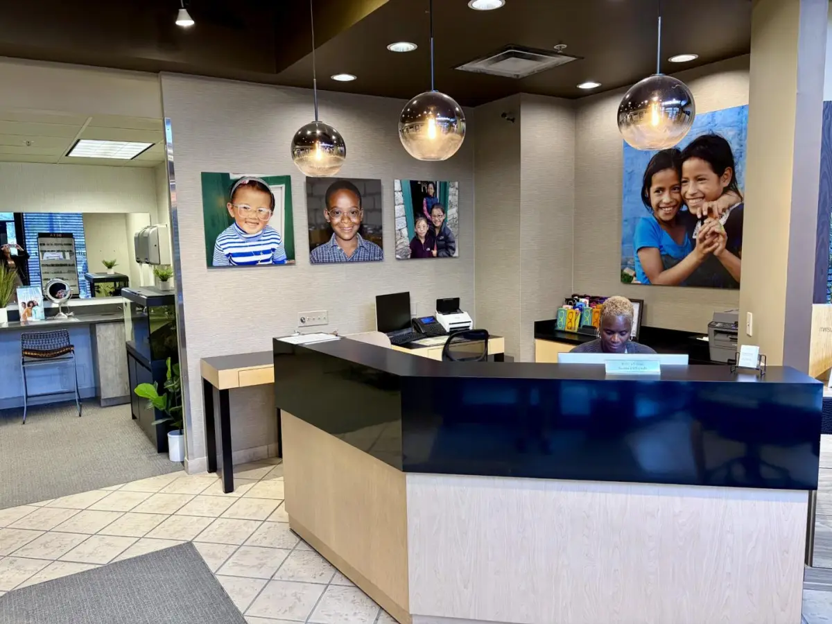 The reception desk at Pelini Eyecare, with the optical to the left and photos from Dr. Pelini’s vision care trips on the wall