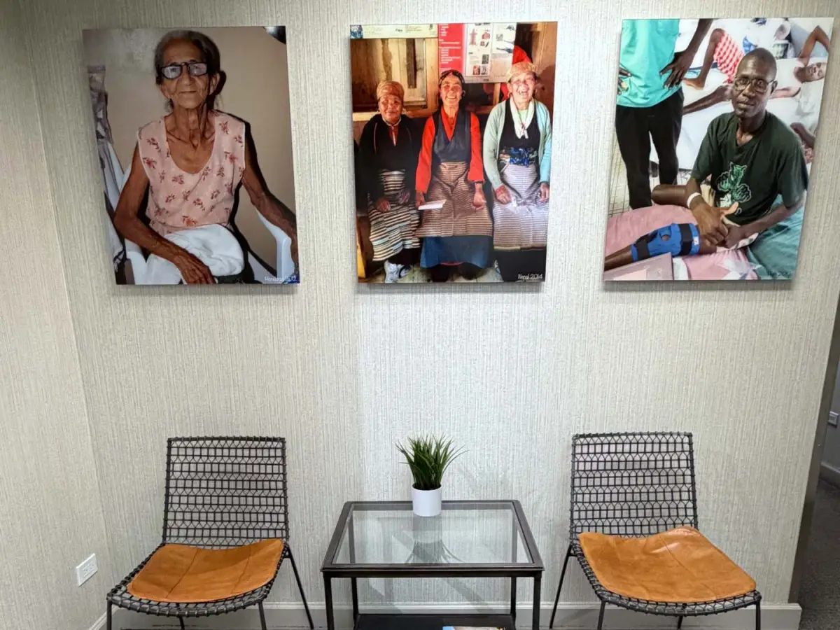 Waiting area chairs beneath photos from Dr. Pelini’s vision care trips abroad